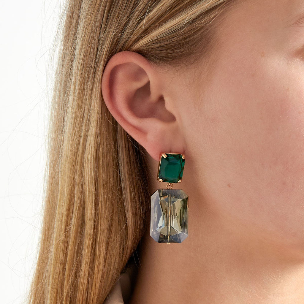 Close-up of a person wearing a green and clear earring.