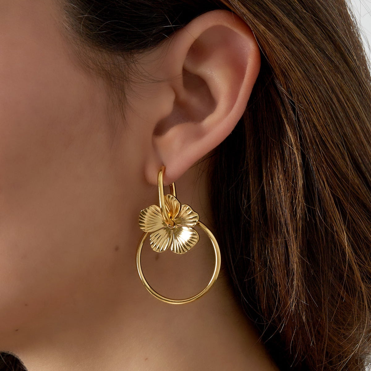 Gold hoop earring worn by a person with brown hair.