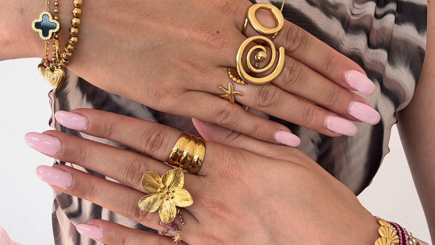Close-up of hands wearing gold jewelry with a neutral background bynooni bynooni.nl 