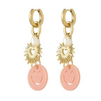 Pair of earrings with gold sun-shaped charms and pink smiley face pendants on a white background