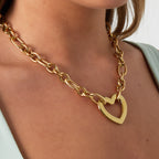 Gold chain necklace with a heart pendant worn by a person.