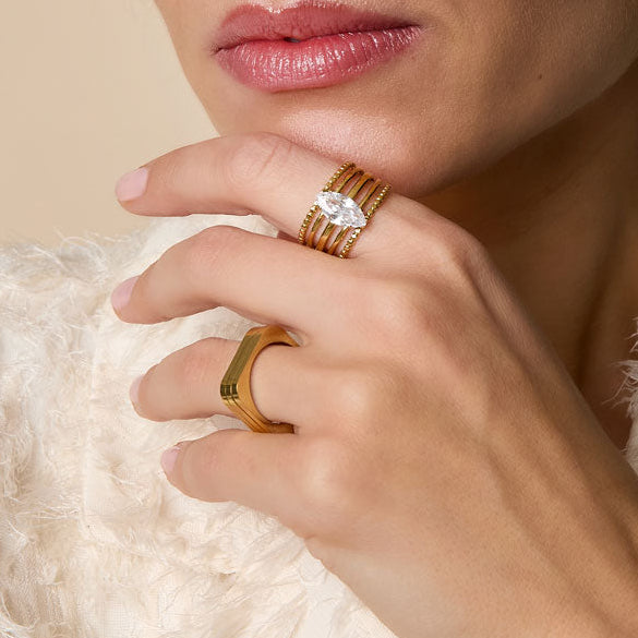 Woman wearing gold jewelry against a beige background