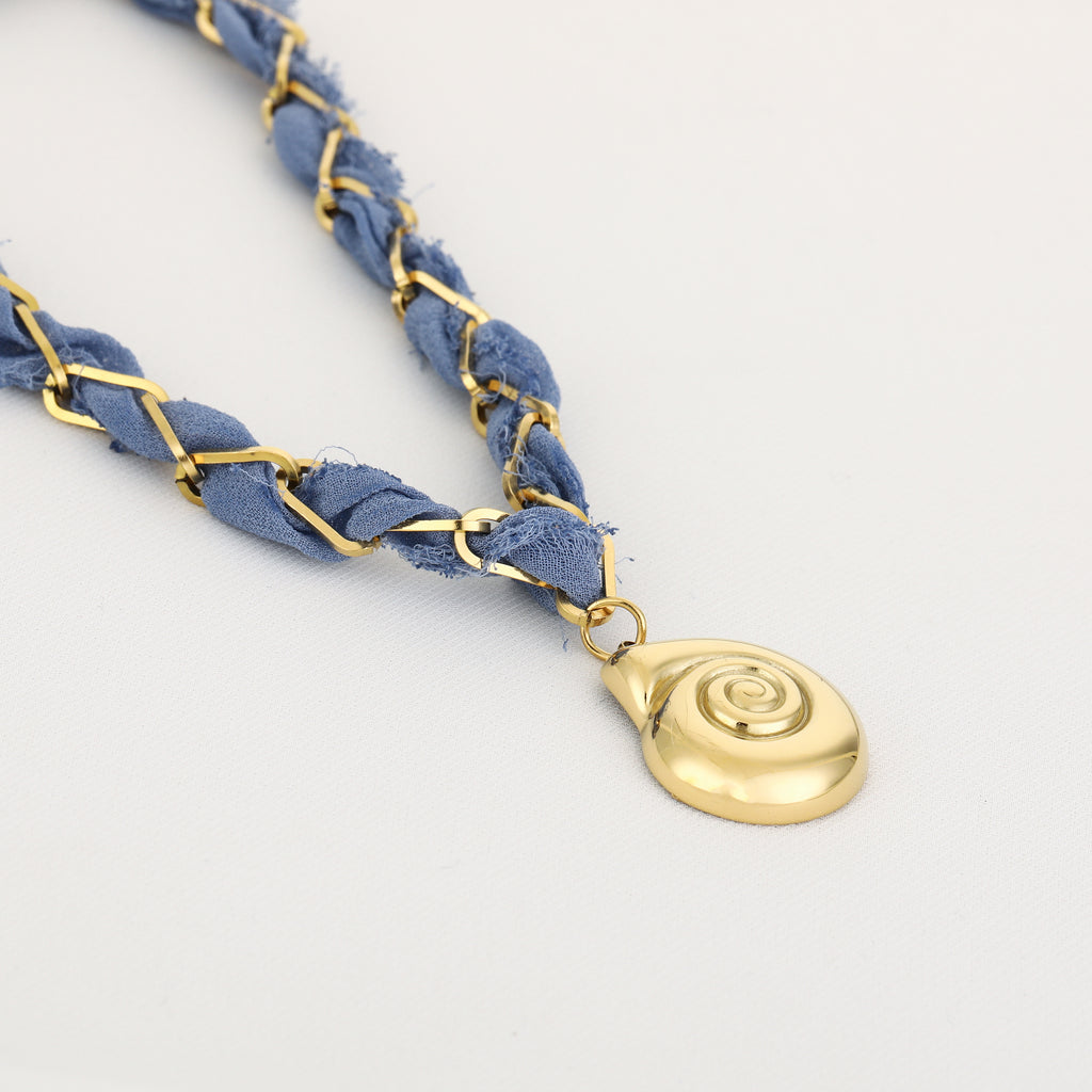 Blue braided bracelet with a gold pendant on a light gray background
