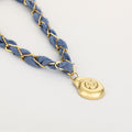Blue braided bracelet with a gold pendant on a light gray background