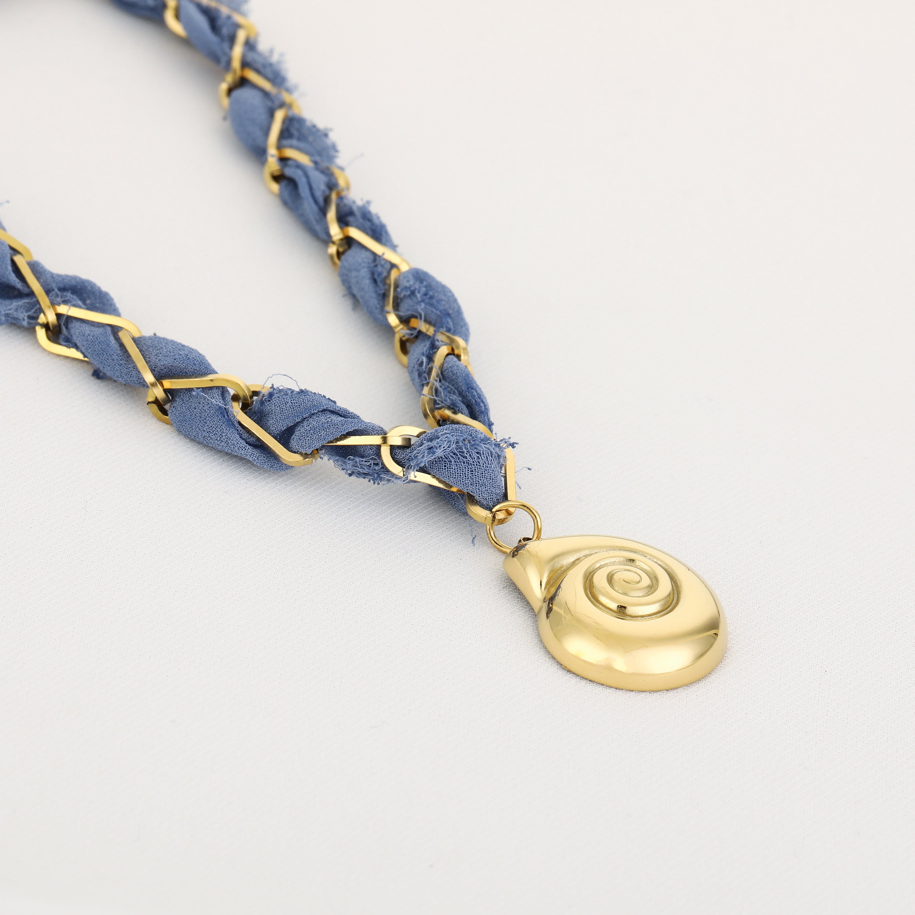 Blue braided bracelet with a gold pendant on a light gray background