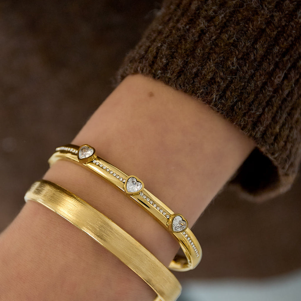 Gold bracelets on a wrist with a blurred background